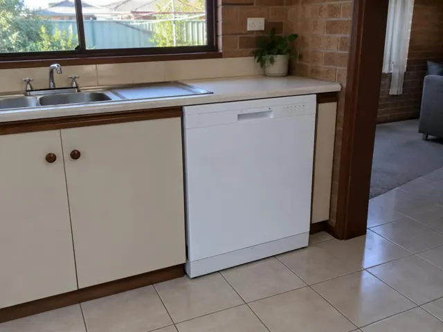Kitchen with built-in dishwasher under laminate bench beside stainless sink in a brick home in Beresfield